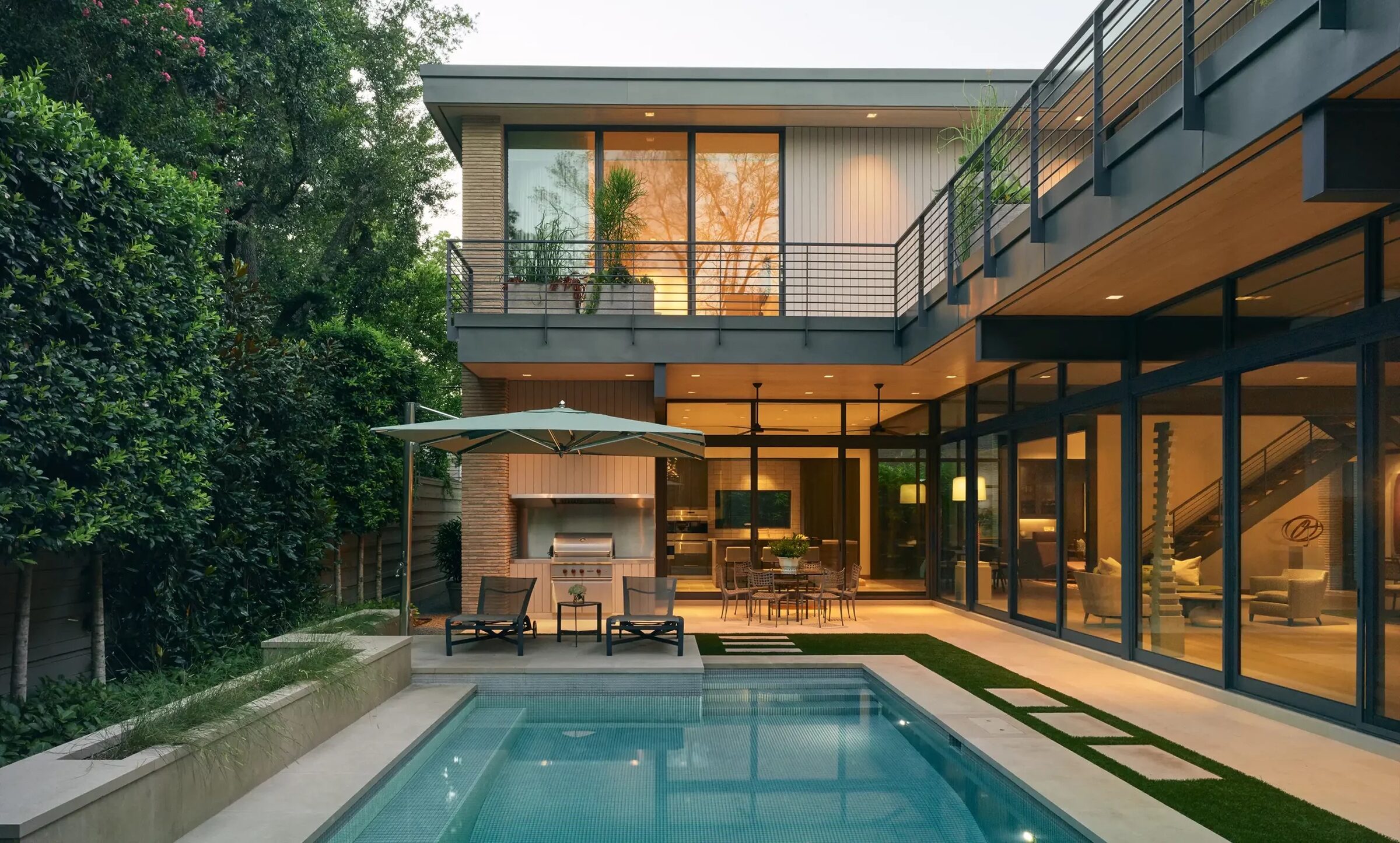Open great room with dining table beyond, glass walls throughout