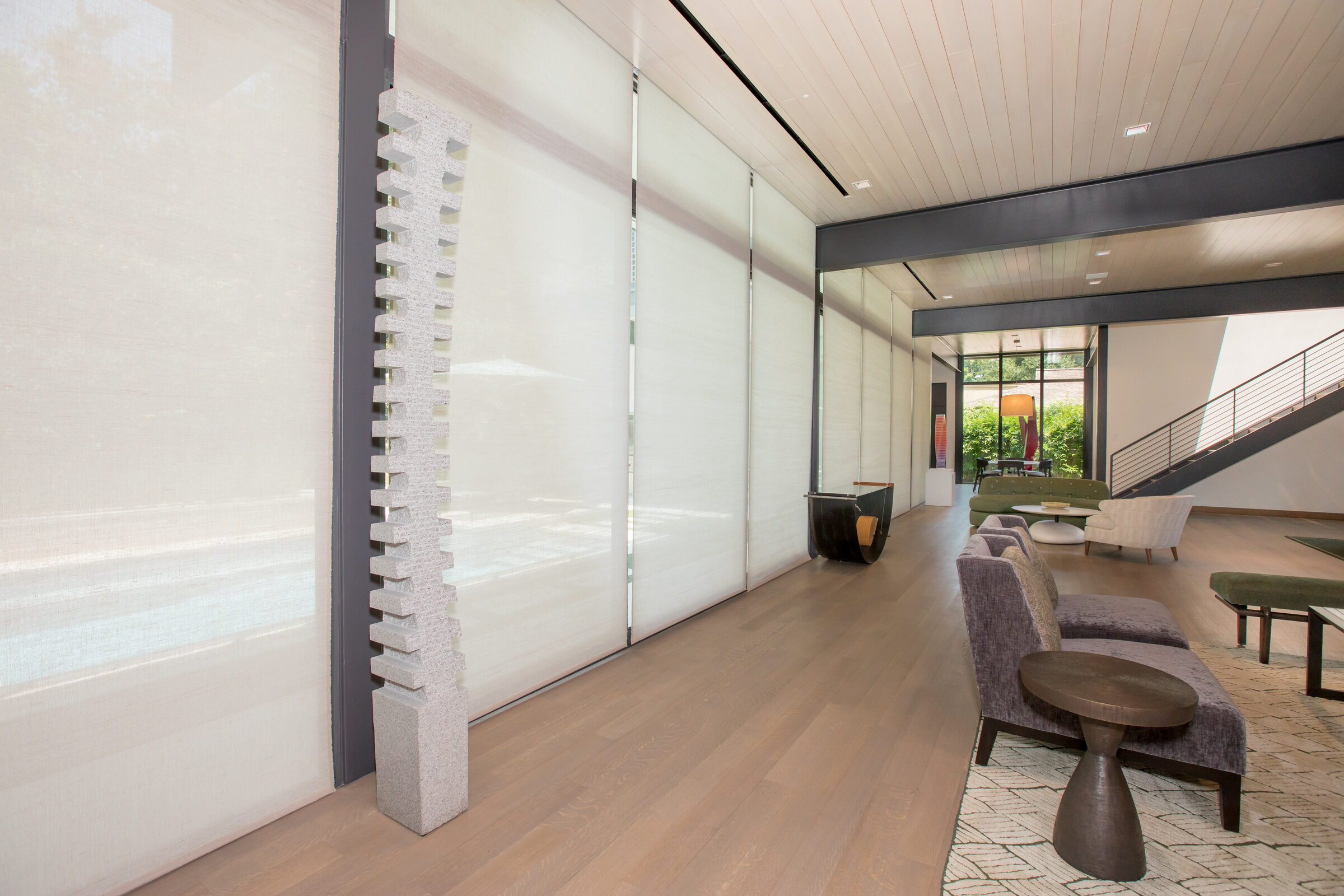 Great room with motorized shades lowered across the floor to ceiling windows